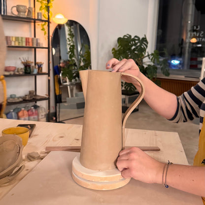 Modelage d’un grand pichet en argile à anse incurvée lors du cours de poterie.