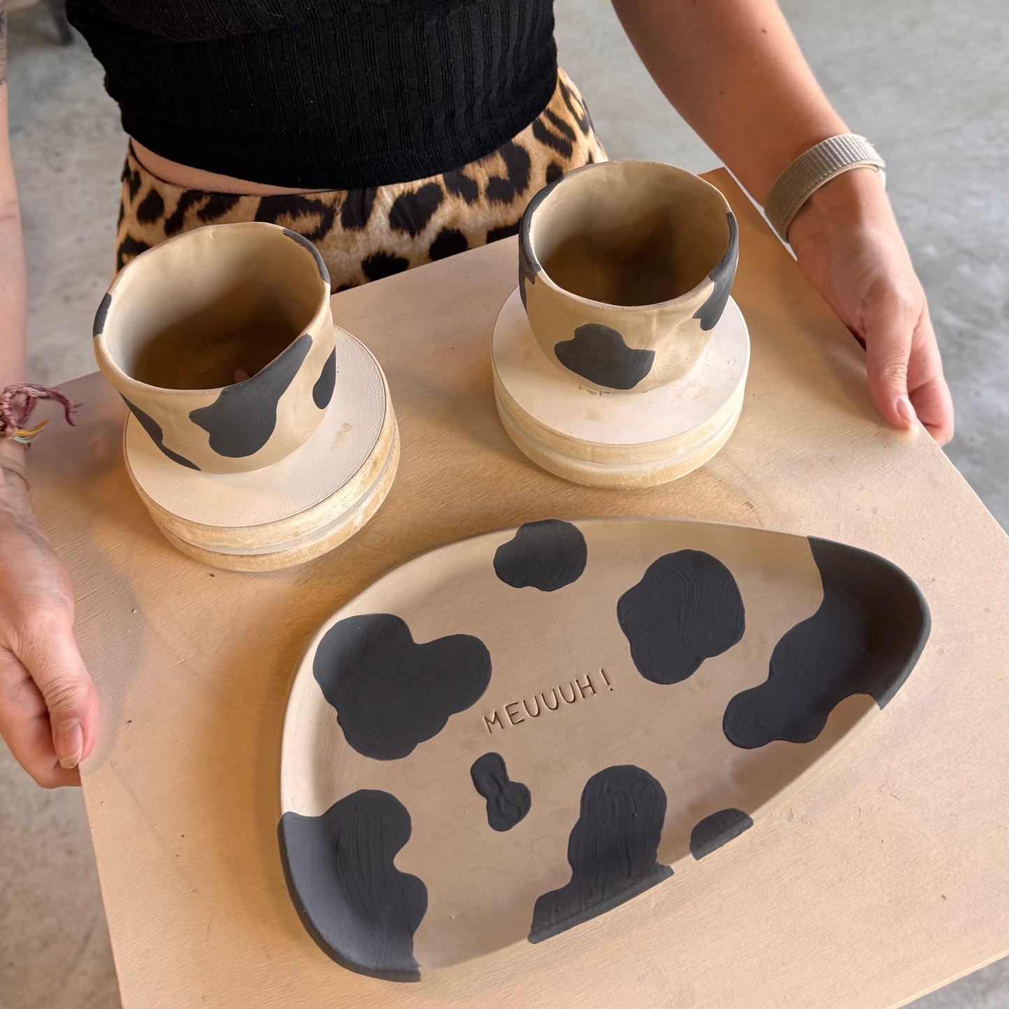 Tasses et plat à motifs de vache réalisés pendant un cours de poterie avec brunch