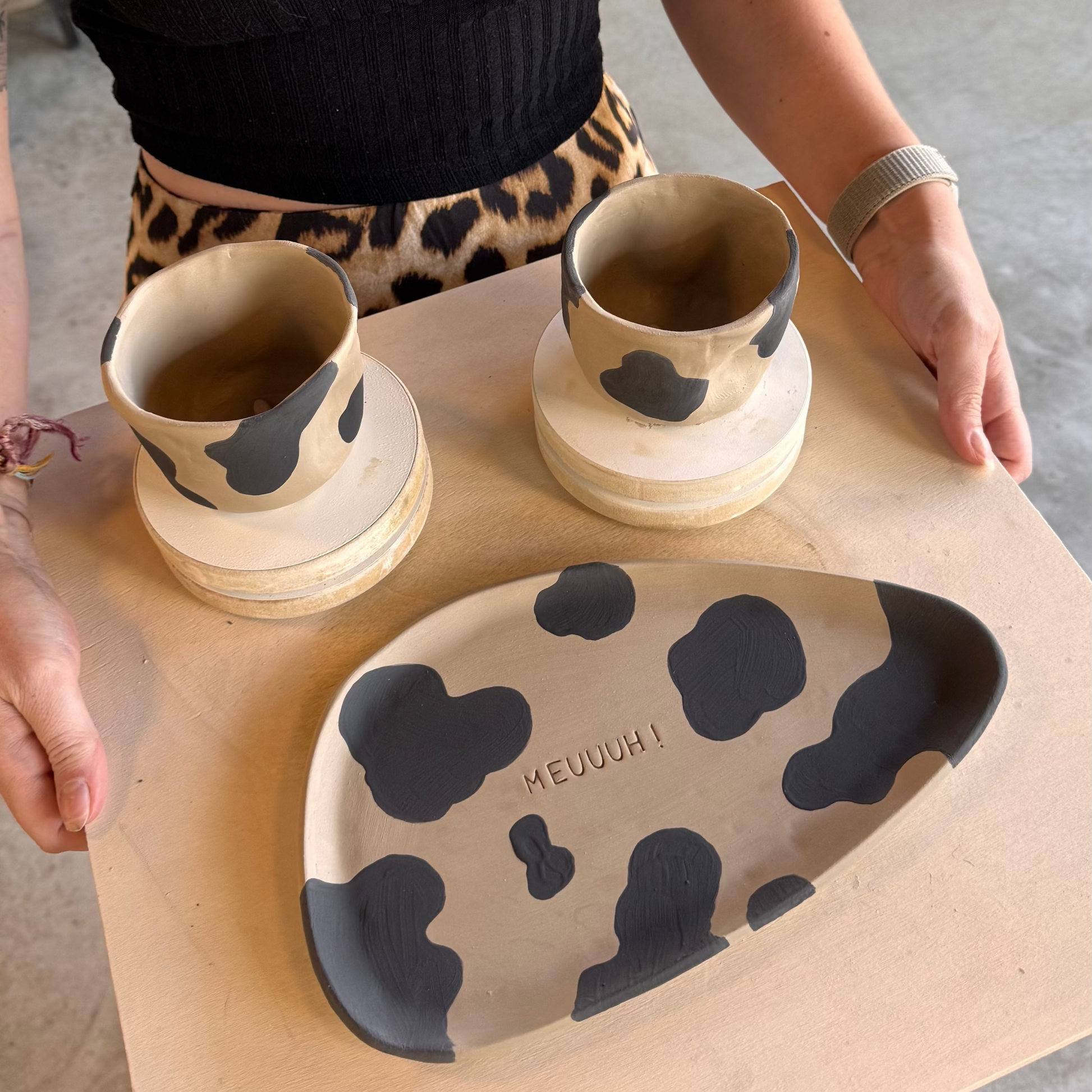 Tasses et plat à motifs de vache réalisés pendant un cours de poterie avec brunch